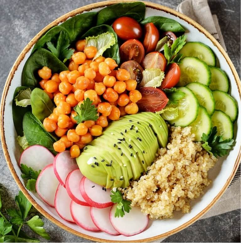 fruits and avocado with woman showing hands in a heart over gut