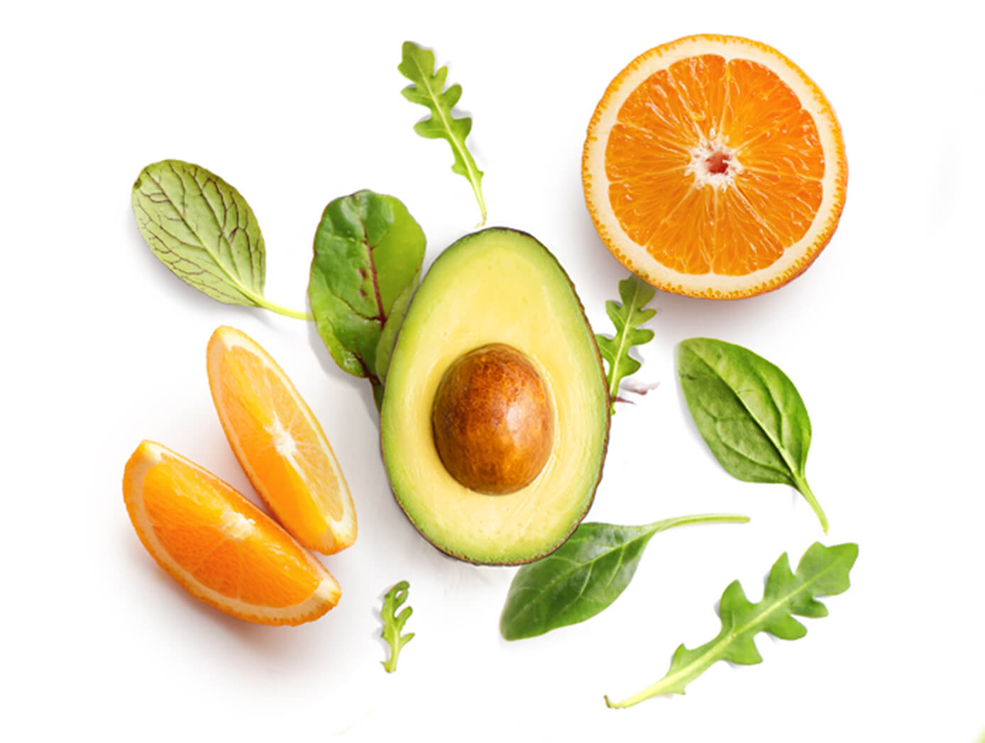 Halved avocado surrounded by orange slices, spinach and arugula leaves